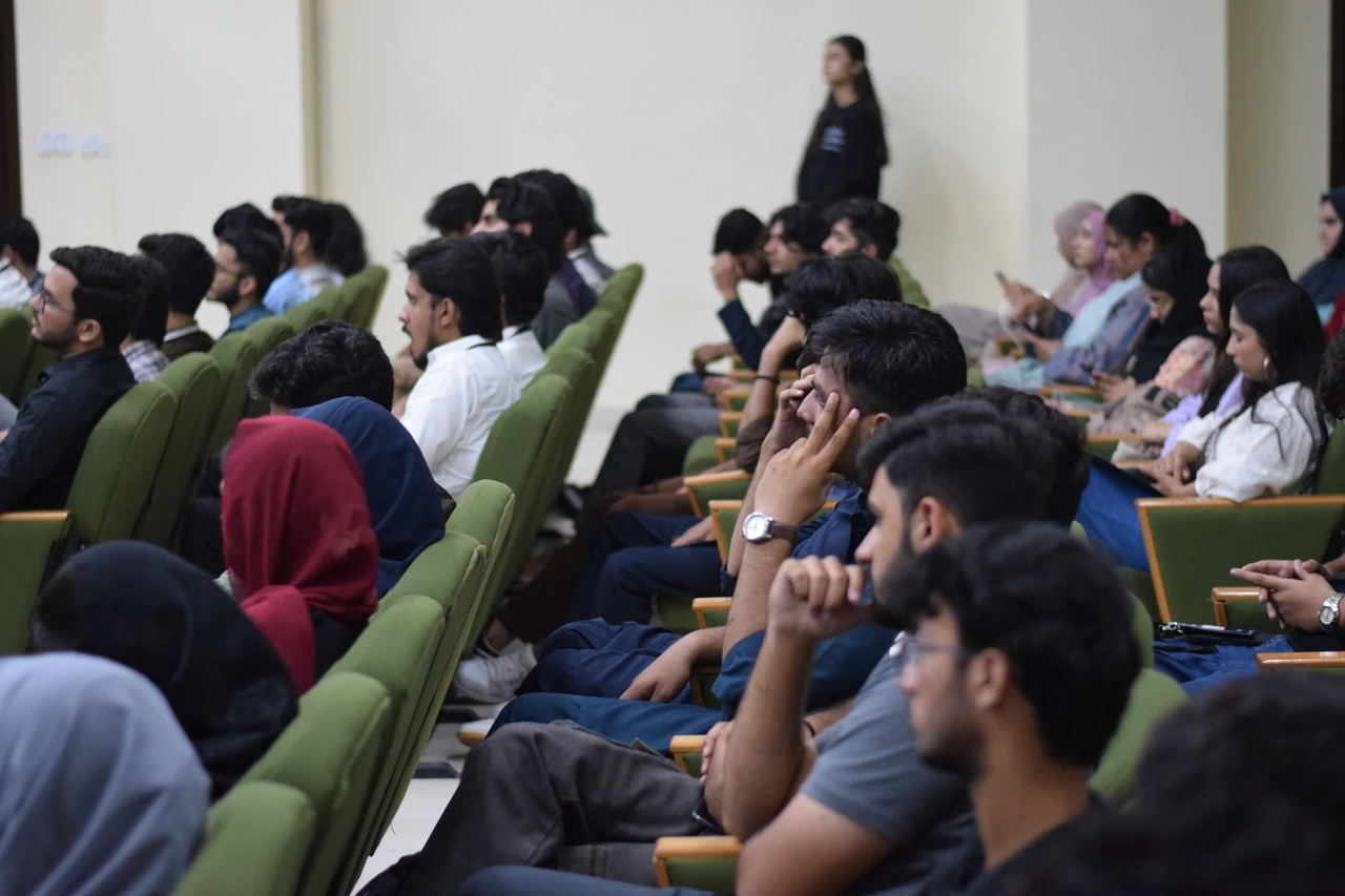 Side view of attendees seated in rows and facing the stage.