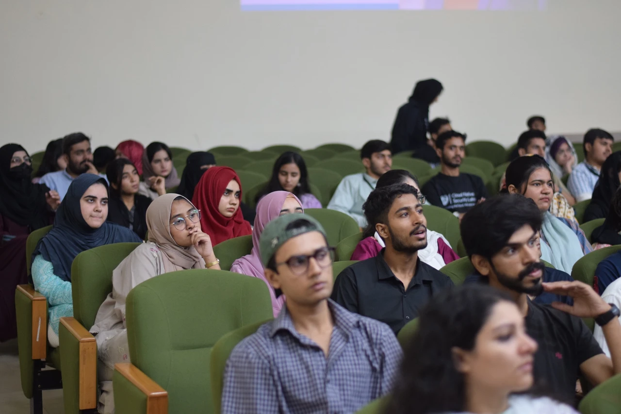 Attendees in the middle rows watch the presentation.