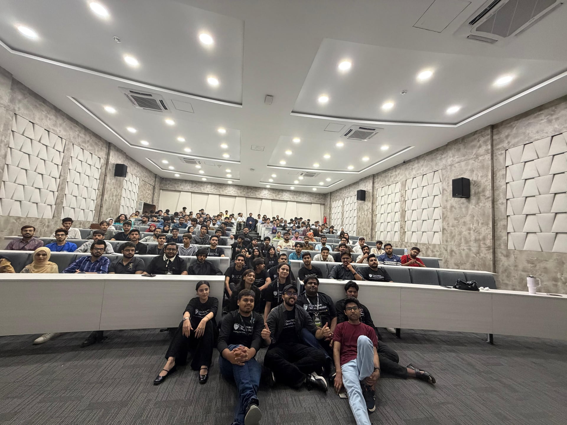 Attendees seated across the tiered lecture hall with organizers gathered at the front
